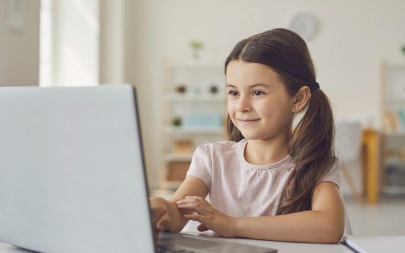 Child attending to an online class at home using their computer