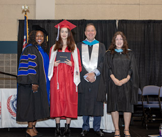 teachers with student receiving the diploma