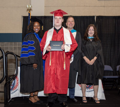 student with teachers receiving the diploma